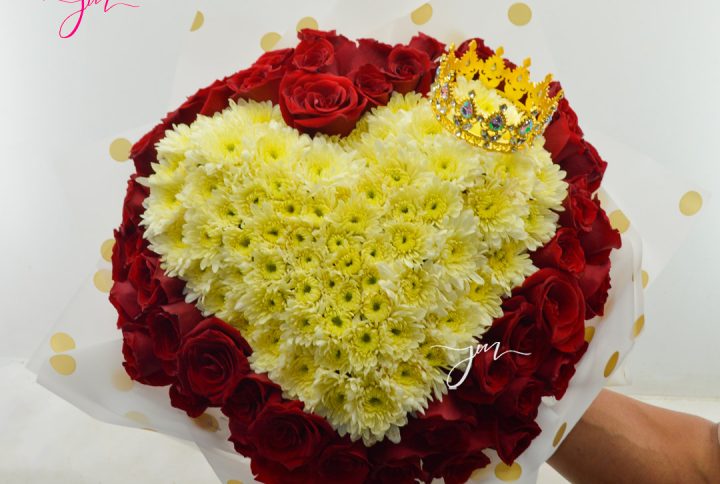 Ramo de flores en forma de corazón con un diseño de crisantemos blancos rodeados de rosas rojas, adornado con una corona dorada.