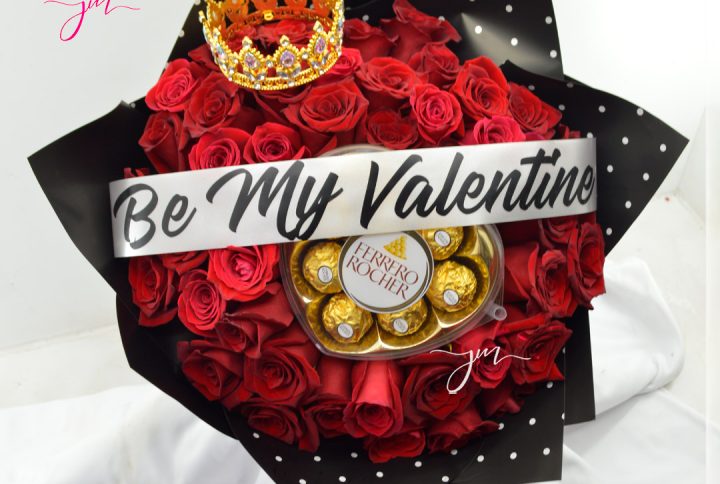 Arreglo con rosas rojas y chocolates Ferrero en forma de corazón, decorado con papel dorado y blanco.