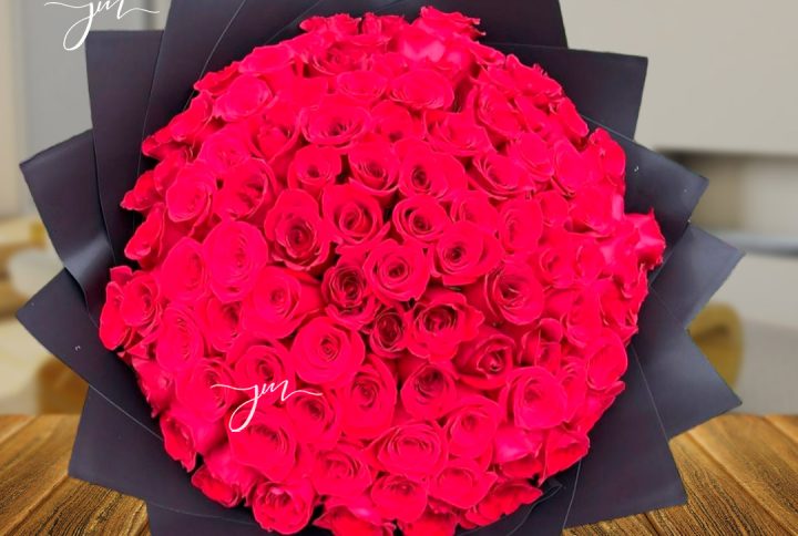 Ramo grande de rosas rojas intensas, envueltas en papel negro elegante.