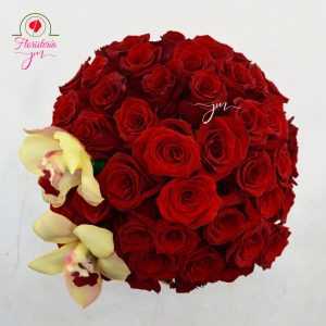Arreglo de rosas rojas en una caja negra decorada con lazos dorados y orquídeas amarillas