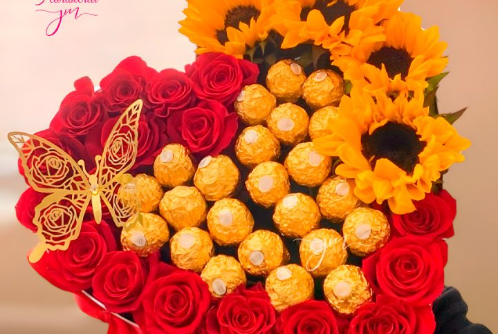 Arreglo en forma de corazón con rosas rojas, girasoles y chocolates Ferrero Rocher.